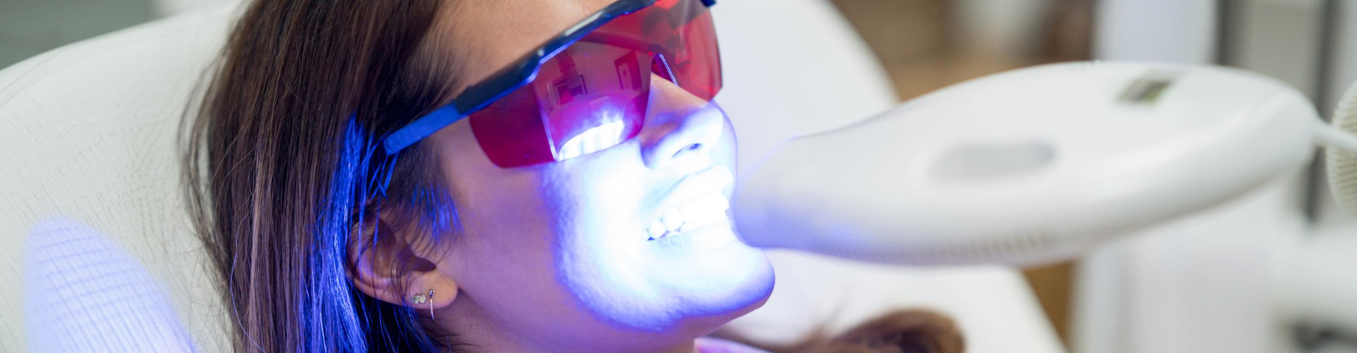 Patient wearing protective glasses during professional teeth whitening treatment before dental veneers procedure.